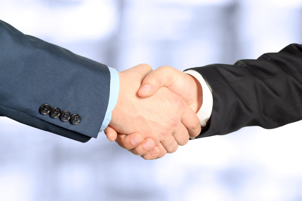 Close-up image of a firm handshake between colleagues in office. Interview